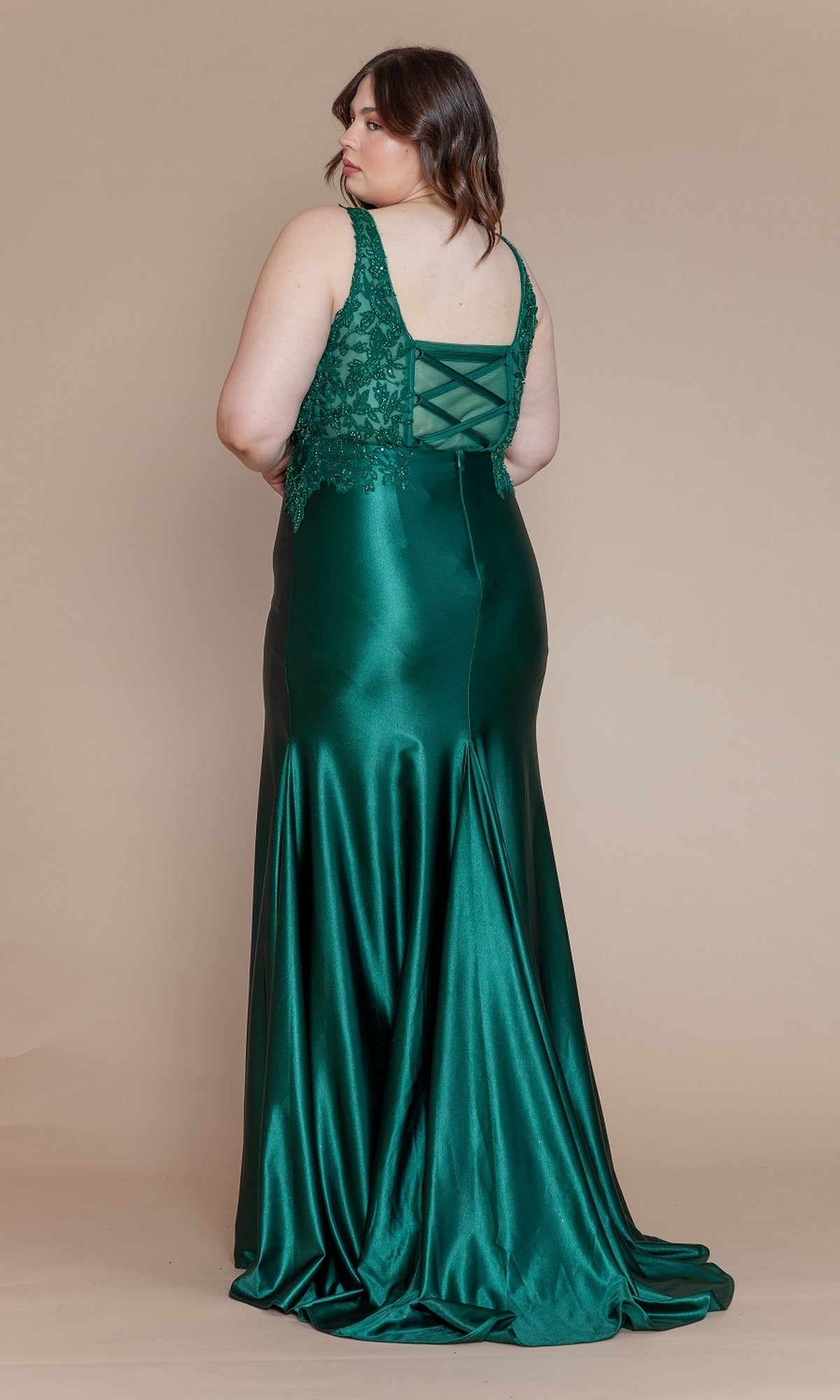 A woman in the Embroidered-Bodice Plus-Size Long Prom Dress W1160, featuring green satin fabric and lace-up corset details, stands facing away on a beige background.